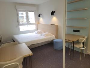 Cette petite chambre comprend un lit, une table et des chaises. dans l'établissement Hôtel et Résidence Les Lauréades Clermont-Ferrand Centre Jaude, à Clermont-Ferrand