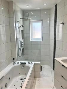 een witte badkamer met een bad en een wastafel bij Gorgeous One Bedroom Apartment with Jacuzzi bath in Hither Green