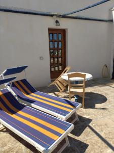 two deckchairs and a chair sitting in a patio at appartamenti del pescatore in Savelletri di Fasano