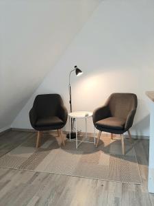 duas cadeiras sentadas ao lado de uma mesa com um candeeiro em Art-Apartment III em Bad Karlshafen