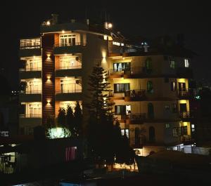 a tall apartment building at night with lights at POKHARA APARTMENTS INN in Pokhara