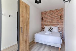ein Schlafzimmer mit einem weißen Bett und einer Ziegelwand in der Unterkunft Magnifique appartement Porte d'Orléans in Montrouge