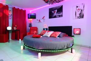 ein Schlafzimmer mit einem Bett in einem Zimmer mit rosafarbener Beleuchtung in der Unterkunft Love Room à deux pas de l'Océan avec Hammam, Sauna et Bain à 2 :-) in Biscarrosse