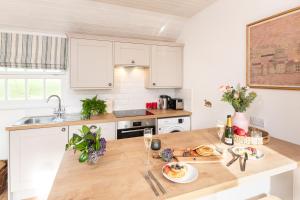 a kitchen with white cabinets and a wooden table at Piglets Retreat in Budleigh Salterton