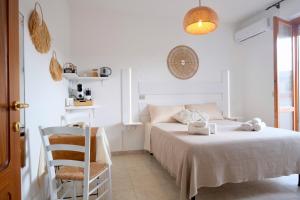 a white bedroom with a bed and a chair at Darrere del port in Alghero