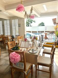 un comedor con mesas, sillas y flores rosas en Monteverde Hotel, en La Dorada