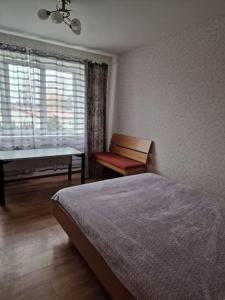 a bedroom with a bed and a bench and a window at Apartamenti dzīvoklis Ogre. in Ogre