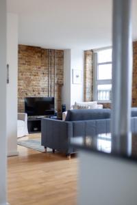a living room with blue couches and a brick wall at Elegance & Chic Design - 2-bedroom Haven in London