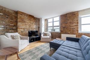 a living room with a brick wall and a blue couch at Elegance & Chic Design - 2-bedroom Haven in London