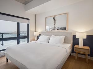 - une chambre avec un lit blanc et une grande fenêtre dans l'établissement Hôtel - Expérience - Quartier Des Marinas, à Magog