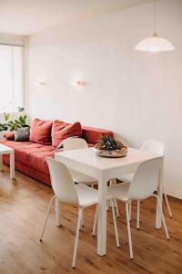 - une table et des chaises blanches dans le salon avec un canapé rouge dans l'établissement 7/504, à Goslar