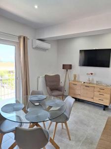 a living room with a table and chairs and a television at Two Brothers Apartments Tsilivi in Planos