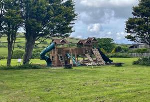a playground with a slide in a field at Bushwood Lodge in Helston