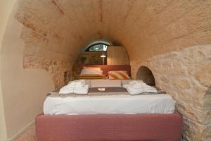 - une chambre avec un lit dans un mur en pierre dans l'établissement Villa Olivida con piscina a sfioro, à Ostuni