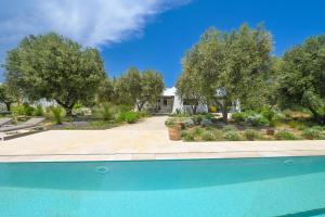 - une piscine en face d'une maison arborée dans l'établissement Villa Olivida con piscina a sfioro, à Ostuni