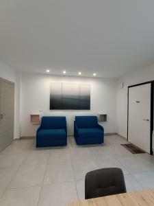 una sala d'attesa con 2 sedie blu e una TV a schermo piatto di Villa Laura Holiday House a Bologna