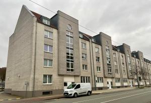 une camionnette blanche garée devant un grand bâtiment en briques dans l'établissement Moderne und gemütliche Wohnung, zentral gelegen, à Bielefeld