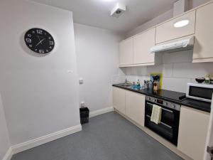 eine Küche mit weißen Schränken und einer Uhr an der Wand in der Unterkunft Eldon Chambers Pod 2 by City Living London in London