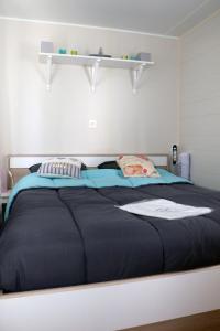 a bedroom with a large bed with a black blanket at Sandilou lesPetitsBonheurs 2 Chambres Climatisé TV in Sigean