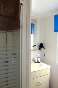 W białej łazience znajduje się umywalka i lustro. w obiekcie Sandilou lesPetitsBonheurs 2 Chambres Climatisé TV w mieście Sigean