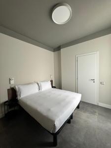 Hotel 22 Marzo في ميلانو: غرفة نوم مع سرير أبيض كبير مع ضوء