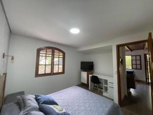 Schlafzimmer mit einem Bett, einem Schreibtisch und einem Fenster in der Unterkunft Confortável Chalet na Serra proximo ao Centro in Nova Friburgo