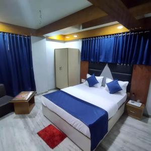 Schlafzimmer mit einem großen Bett und blauen Vorhängen in der Unterkunft HOTEL SHREE RADHE in Ahmedabad