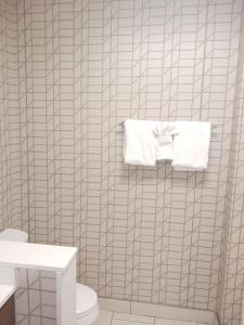 a bathroom with white tiled walls and a toilet and towels at Holiday Inn Express & Suites Gainesville - Lake Lanier Area, an IHG Hotel in Gainesville