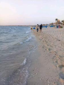 um grupo de pessoas caminhando na praia em قرية النورس مكتب السعد em Ismaília