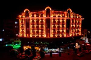 een groot gebouw dat 's nachts verlicht wordt bij Can Adalya Palace Hotel in Antalya