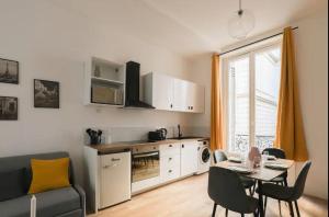 ein Wohnzimmer mit einer Küche und einem Tisch mit Stühlen in der Unterkunft Charmant appartement proche Opéra Garnier - 4p in Paris