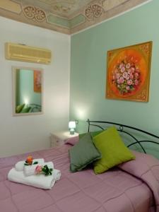 - une chambre avec un lit violet et 2 serviettes dans l'établissement Regina Stella, à Lascari