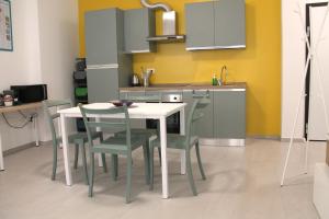 a kitchen with a white table and green chairs at FaCentro - Pratico flat in centro storico in Faenza