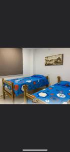 a bedroom with two beds with a blue comforter at Hostal Los Arhuacos in Santa Marta