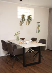 a dining room table with chairs and a white table at Zum Brandenburger Tor, Ferienwohnung im Herzen von Damme in Damme