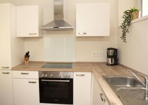 a kitchen with white cabinets and a stove and a sink at Zum Brandenburger Tor, Ferienwohnung im Herzen von Damme in Damme