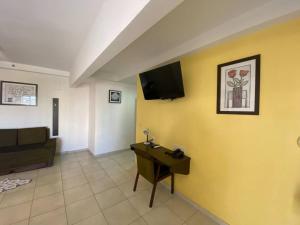 a living room with a couch and a tv on a yellow wall at Flat Amplo em frente USP/FOB in Bauru