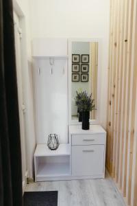 un comò bianco con una pianta in vaso sopra di Apartman Silver room a Sombor