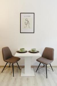 un tavolo bianco con due sedie e una foto sul muro di Apartman Silver room a Sombor