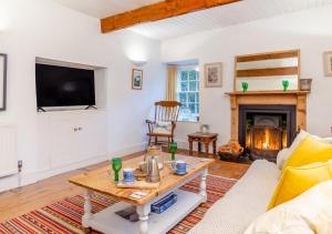 a living room with a table and a fireplace at Ball Cottage in Little Petherick