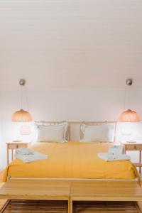 a bedroom with a yellow bed with two lamps at Melides Loft Teatro in Melides