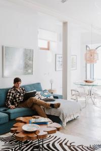 a man sitting on a couch with a laptop at Melides Loft Teatro in Melides +32 photos