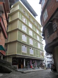 um edifício verde e amarelo numa rua da cidade em Pemathang Hotel em Gangtok