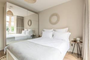 a bedroom with a large white bed and a mirror at Blu's Seaview Apartment in Llandrillo-yn-Rhôs