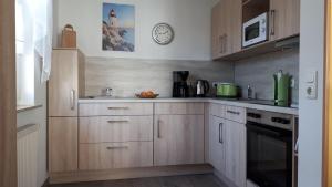 a kitchen with wooden cabinets and a clock on the wall at Strandschloesschen-Haus-II-WE-17-9871 in Kühlungsborn