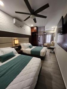 Habitación de hotel con 2 camas y ventilador de techo. en Hotel Tepeu, en Santa Elena