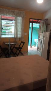 a kitchen and dining room with a table and a refrigerator at Suítes Vila do Surf , a original , desde 2010 in Ubatuba