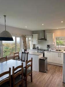 Pencaer Holiday Cottage في Goodwick: مطبخ وغرفة طعام مع طاولة وكراسي