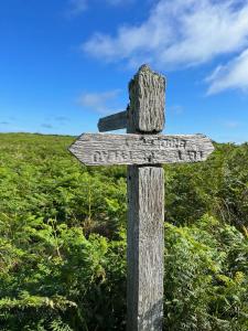 a wooden sign on the side of a field at Pencaer Holiday Cottage in Goodwick