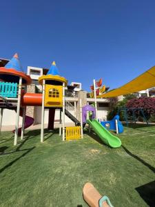 un parque infantil con diferentes toboganes de colores en el césped en Family Sweet - Apartment in Tala Bay Aqaba, en Al Burj